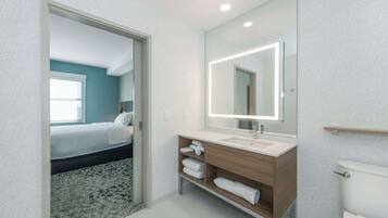 Une salle de bain moderne avec un grand miroir, un lavabo blanc et des toilettes.