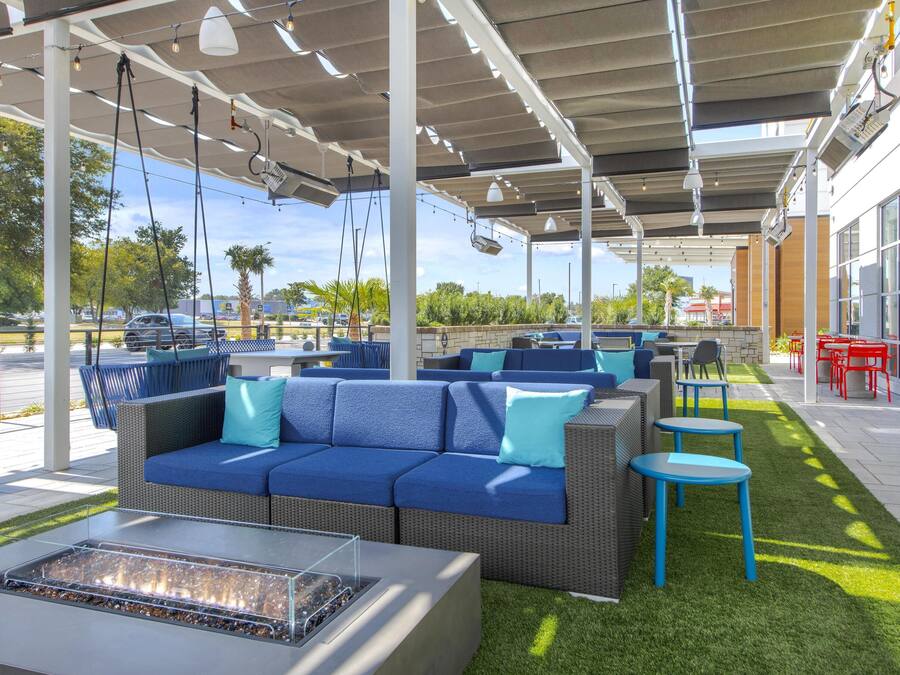 An outdoor patio area with wicker furniture, a fire pit, and a view of the parking lot.