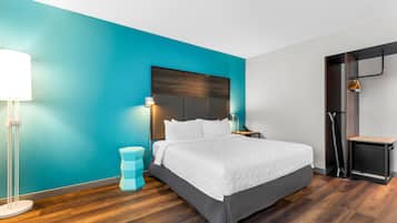 A modern hotel room with a large bed, a nightstand, a lamp, and a wardrobe.