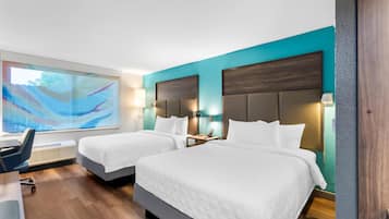 Habitación de hotel con dos camas, un escritorio y un cuadro abstracto grande en la pared.