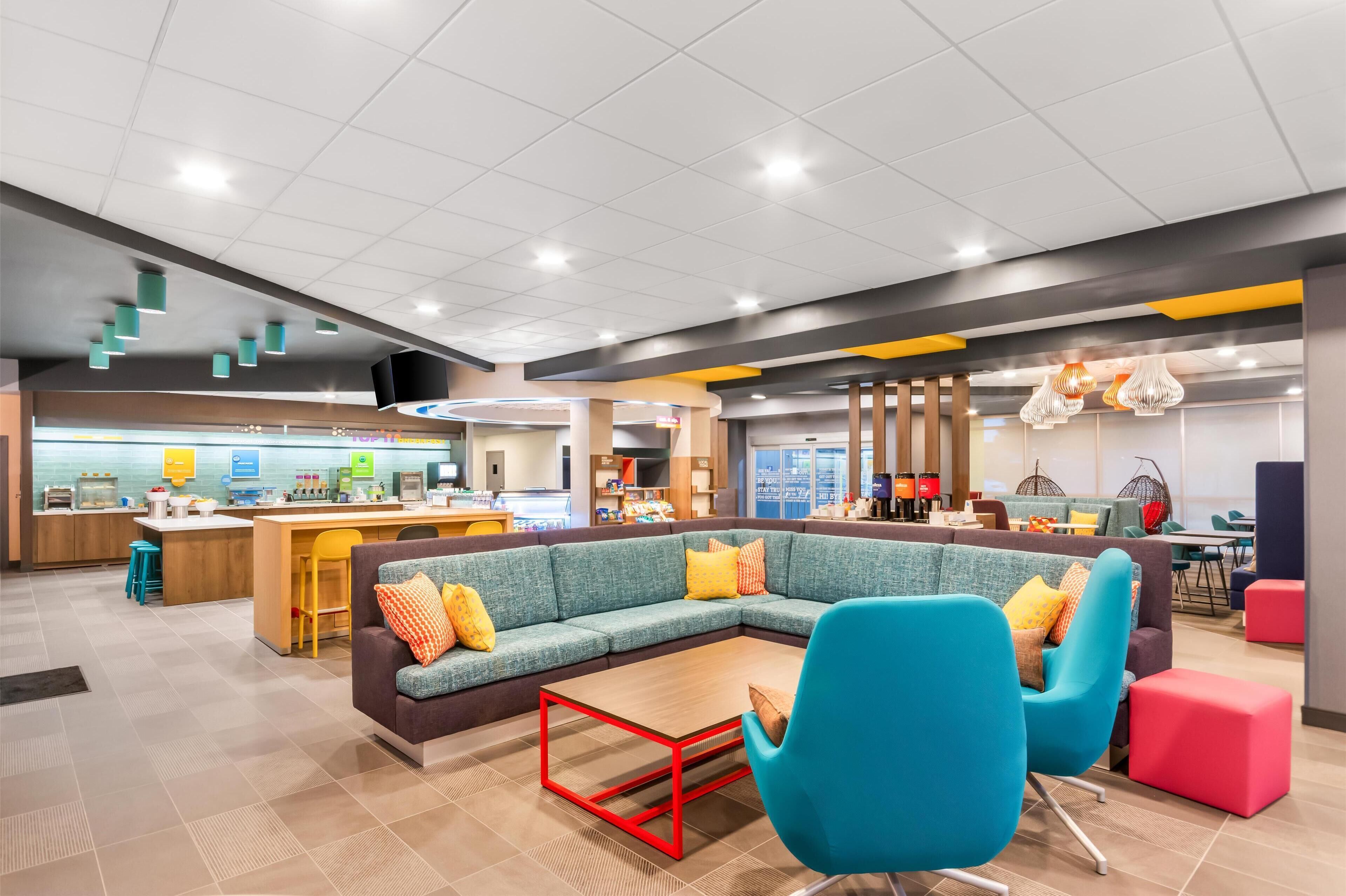 A modern lounge area with a central seating area, a bar, and various dining options.