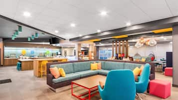 A modern lounge area with a central seating area, a bar, and various dining options.