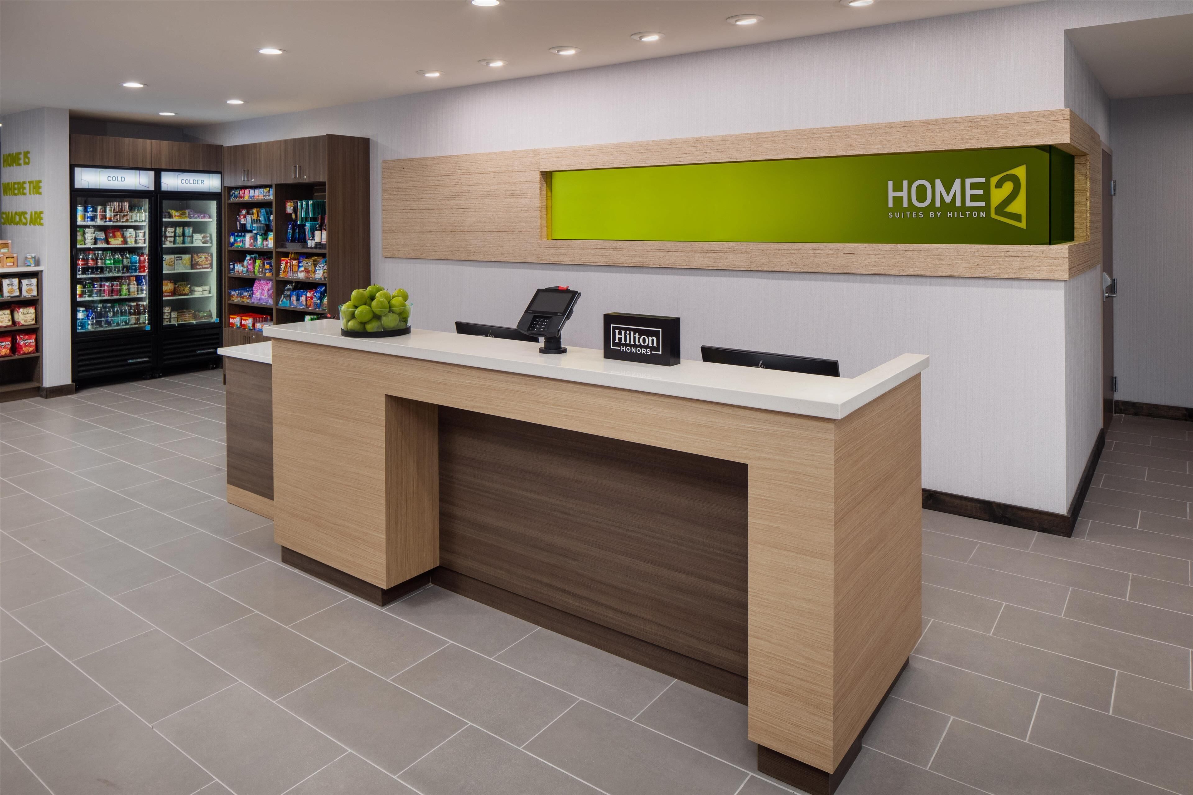 Ein Hotelrezeptionstresen mit digitalem Display, einer Minibar und einem Selbstbedienungsgetränkeautomaten.