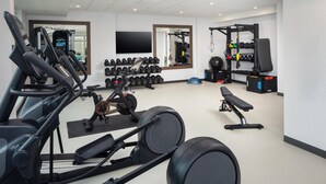 Un gimnasio moderno con máquinas de cardio, pesas libres y una jaula para sentadillas.