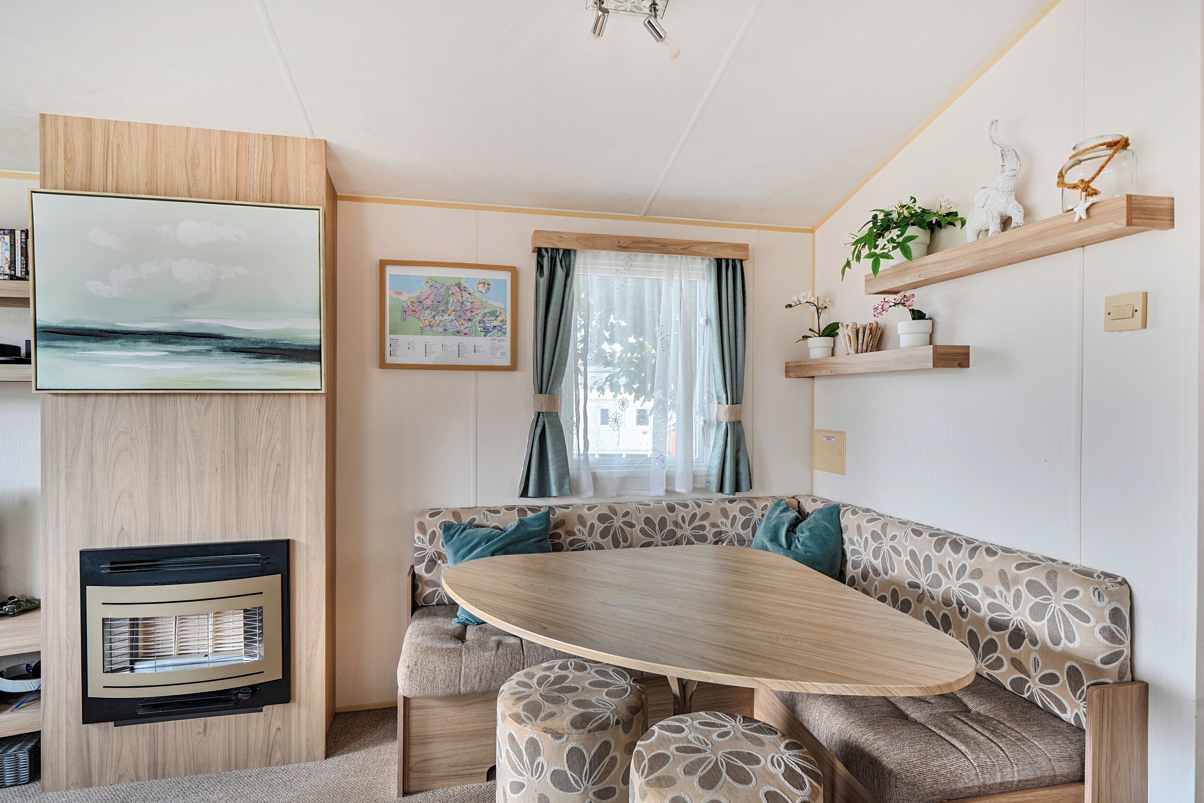 Un intérieur chaleureux avec une table à manger en bois, des sièges confortables, une carte accrochée au mur et une fenêtre avec des rideaux.
