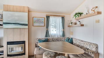 A cozy interior with a wooden dining table, cushioned seating, a map on the wall, and a window with curtains.
