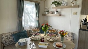 Een gezellige eethoek met een ronde tafel gedekt voor een maaltijd, omringd door een bank met gestreepte kussens.