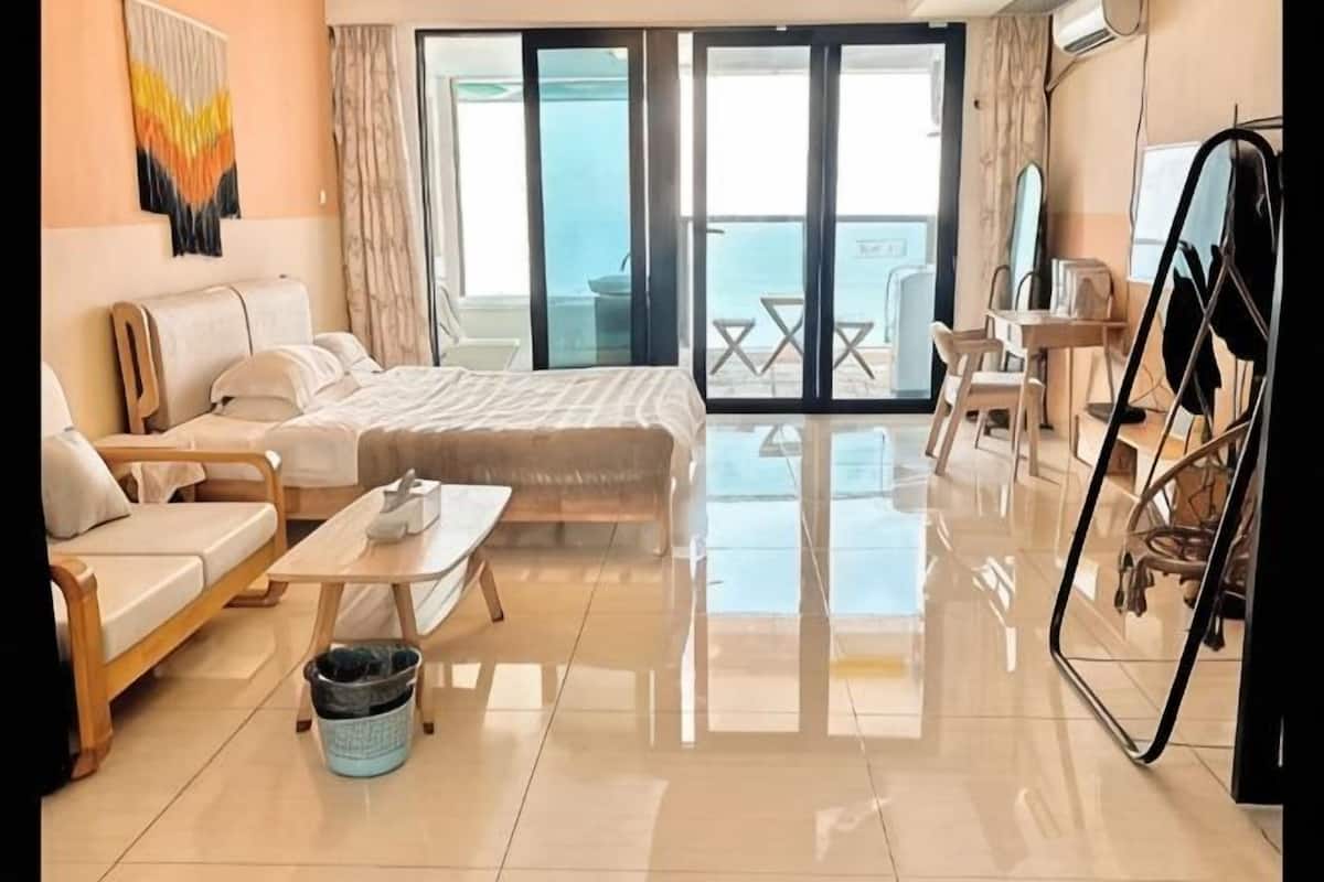 A modern hotel room with a bed, sofa, and dining table.