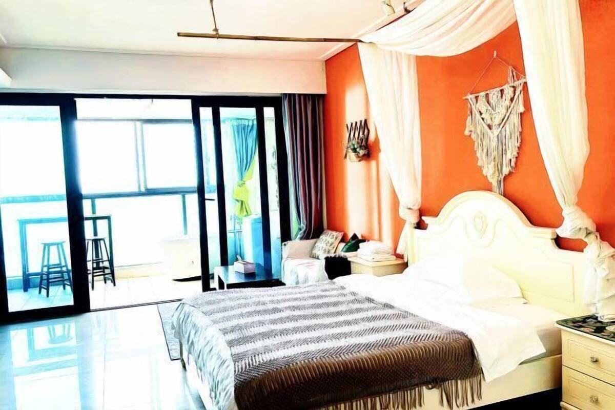Ein Schlafzimmer mit Bett, Nachttisch, Stuhl und Blick ins Freie.