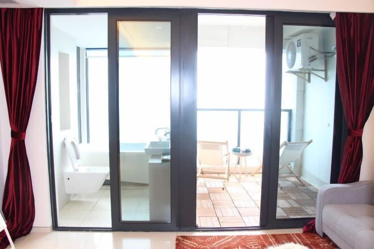 Ein Zimmer mit einer Schiebetür und einem Balkon, auf dem ein weißes Waschbecken und ein Stuhl stehen.
