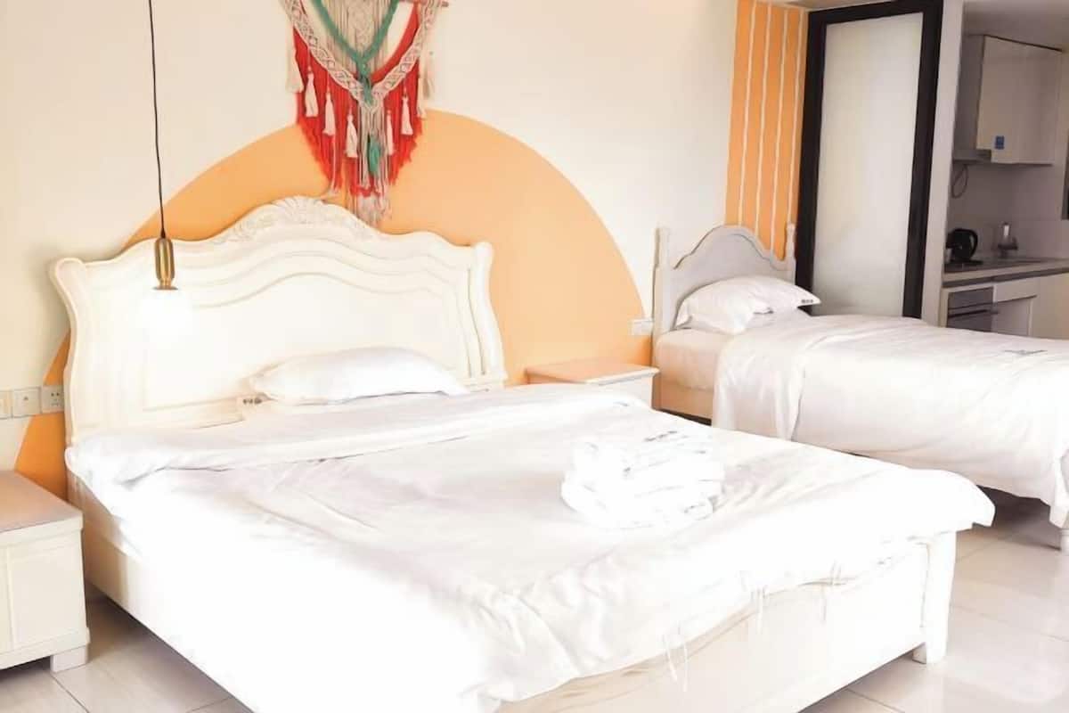 Ein Hotelzimmer mit zwei Betten, einem großen Spiegel und einer Küchenzeile.