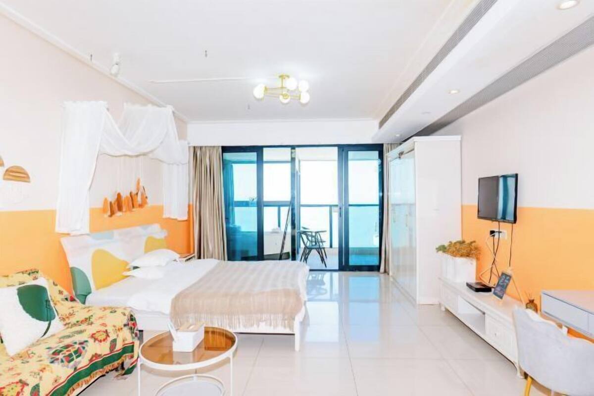 Ein Hotelzimmer mit Bett, einer Couch, einem kleinen Tisch, einem Fernseher und einem Balkon mit Blick.