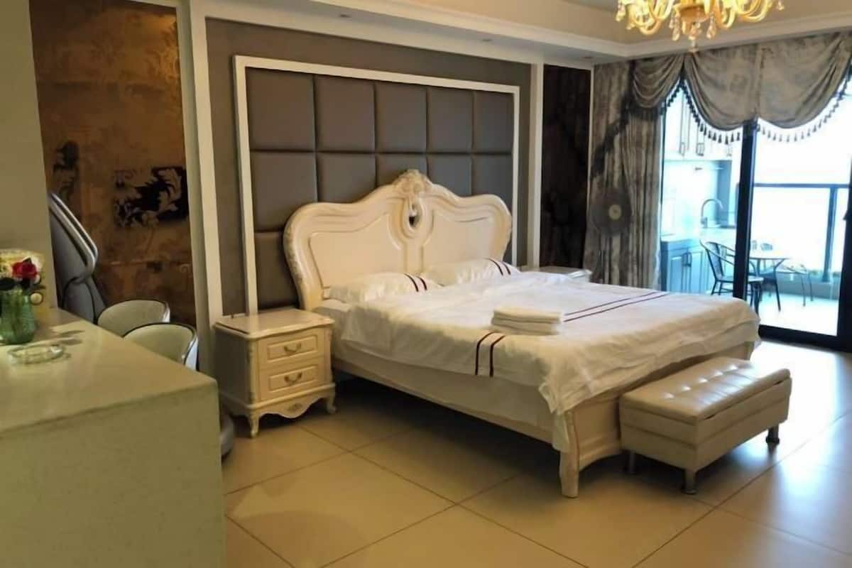 Ein Schlafzimmer mit Bett, Nachttischen, einer Bank und Blick ins Freie.