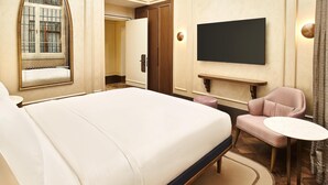 A hotel room with a large bed, a television mounted on the wall, a small round table, and a seating area with a chair. - Les Temps Istanbul Karakoy, Curio Collection By Hilton (Istanbul)