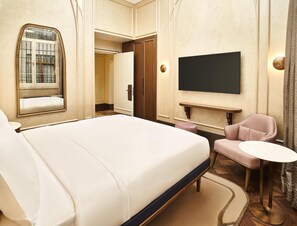 A hotel room with a large bed, a television mounted on the wall, a small round table, and a seating area with a chair. - Les Temps Istanbul Karakoy, Curio Collection By Hilton (Istanbul)