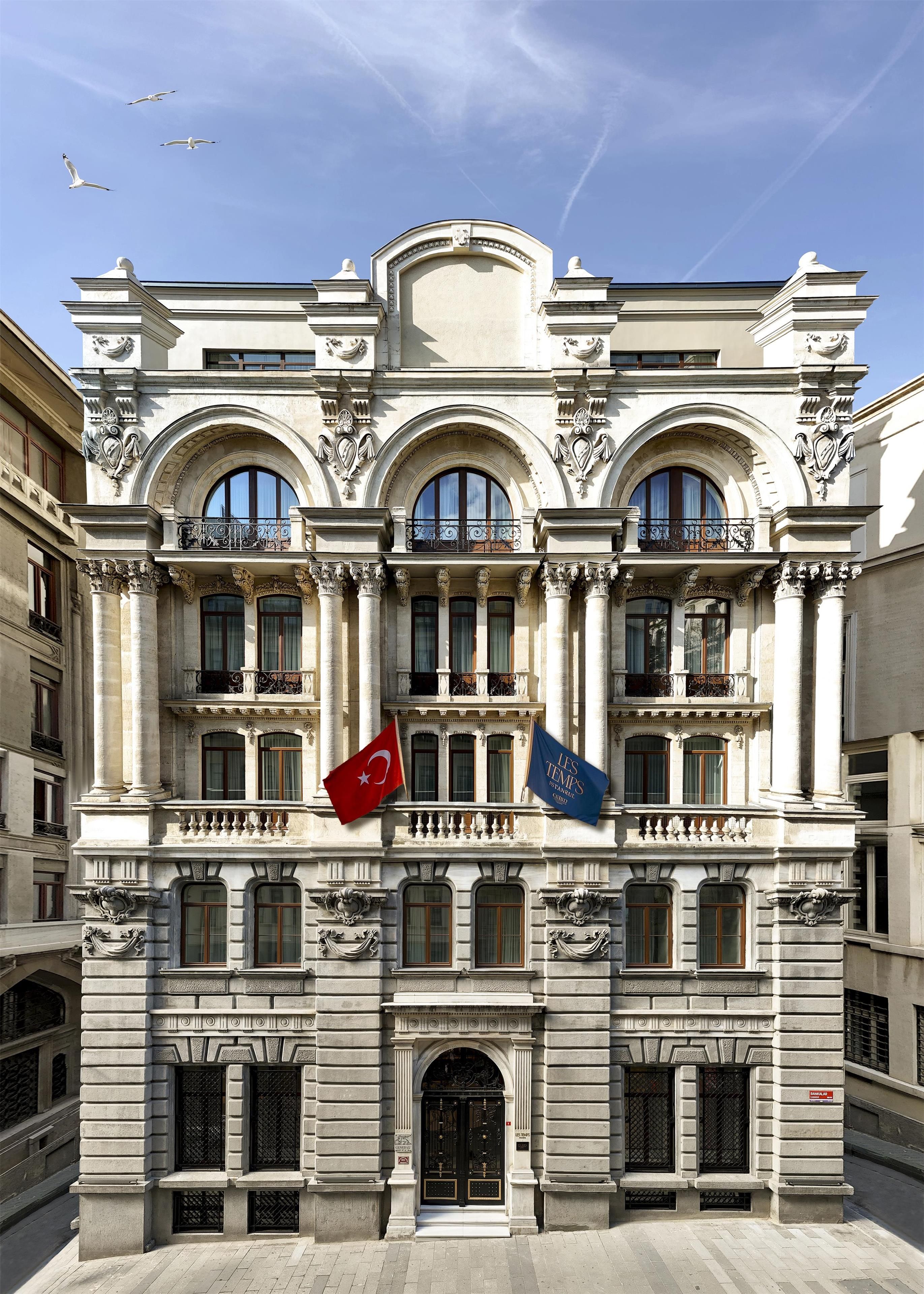 Un edificio storico con architettura elaborata, diversi balconi e bandiere.