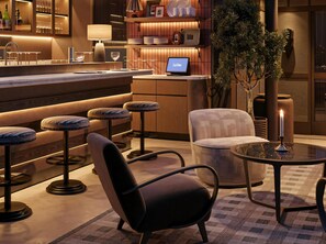 A modern bar area with stools, a bar counter, a laptop, and a candle on a table. - Les Temps Istanbul Karakoy, Curio Collection By Hilton (Istanbul)
