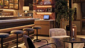 A modern bar area with stools, a bar counter, a laptop, and a candle on a table. - Les Temps Istanbul Karakoy, Curio Collection By Hilton (Istanbul)