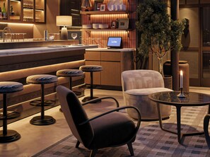 A modern bar area with stools, a bar counter, a laptop, and a candle on a table. - Les Temps Istanbul Karakoy, Curio Collection By Hilton (Istanbul)