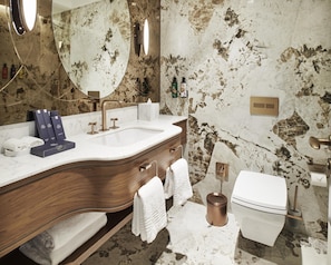 A bathroom with a marble sink, wooden vanity, a large mirror, and a white toilet. - Les Temps Istanbul Karakoy, Curio Collection By Hilton (Istanbul)