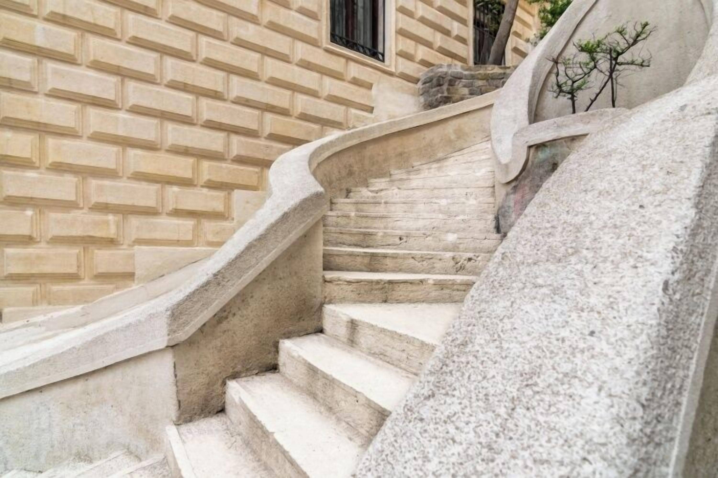 A stone staircase with a curved handrail leading to a door with a window.