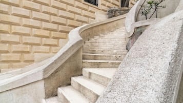 A stone staircase with a curved handrail leading to a door with a window.