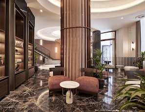 A lobby with a marble floor, a staircase, seating area, and a bookshelf.