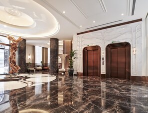 A spacious lobby with marble flooring, a central column, and two elevators. - Les Temps Istanbul Karakoy, Curio Collection By Hilton (Istanbul)