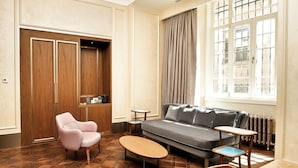 A room with a sofa, a chair, a small table, a radiator, and a window with curtains. - Les Temps Istanbul Karakoy, Curio Collection By Hilton (Istanbul)