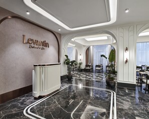 A hotel lobby with a reception desk, seating area, and a large window.