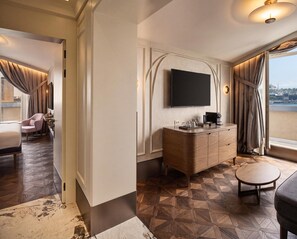 A hotel room with a modern design, featuring a large flat-screen TV mounted on the wall, a wooden vanity with a mirror, and a small round table. - Les Temps Istanbul Karakoy, Curio Collection By Hilton (Istanbul)