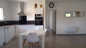 A modern kitchen with white cabinetry, a central island, and a dining area with chairs.