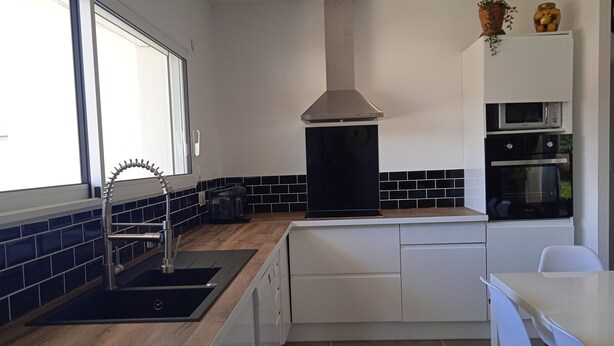 A modern kitchen with a black stove, white cabinets, and a window providing natural light.