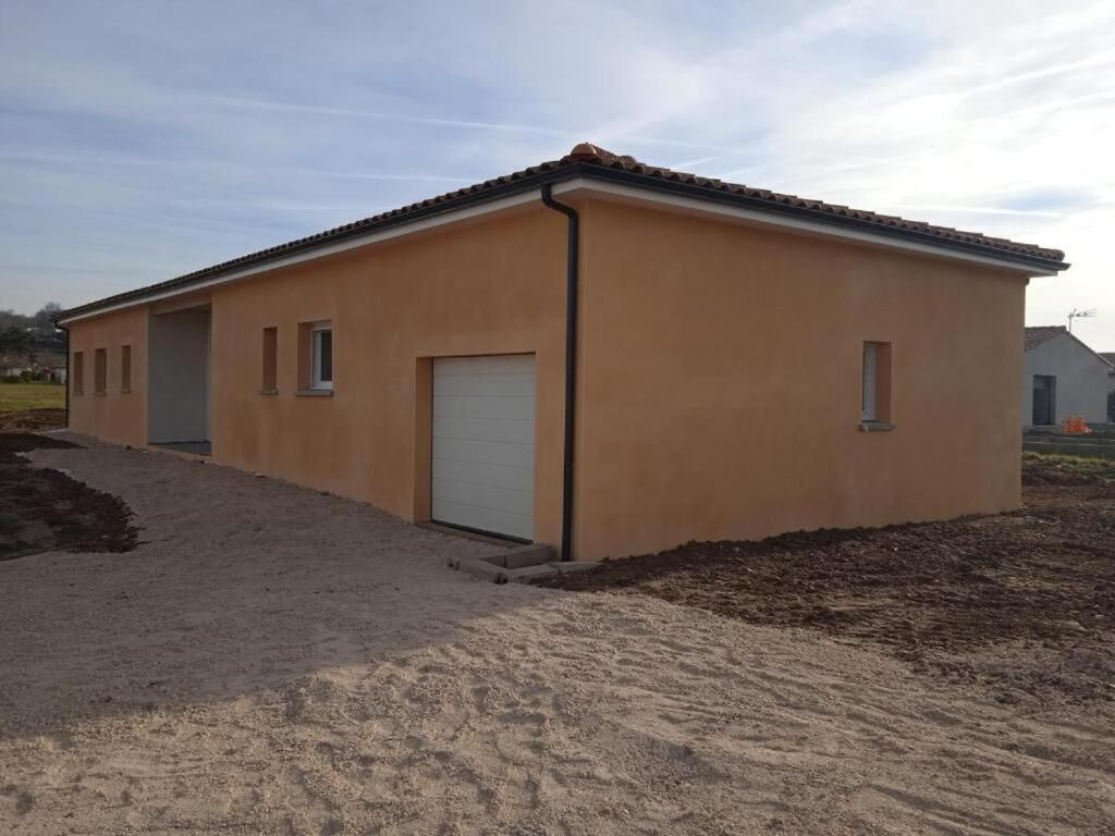 Um edifício térreo com telhado plano, uma porta branca e uma pequena janela lateral.