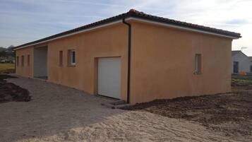Um edifício térreo com telhado plano, uma porta branca e uma pequena janela lateral.