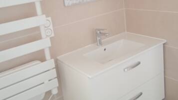 A bathroom with a white vanity, a mirror, and a towel rack.
