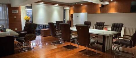 A conference room with a wooden floor, a white table, and several chairs.