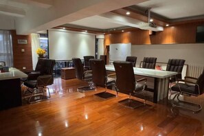 A conference room with a wooden floor, a white table, and several chairs.