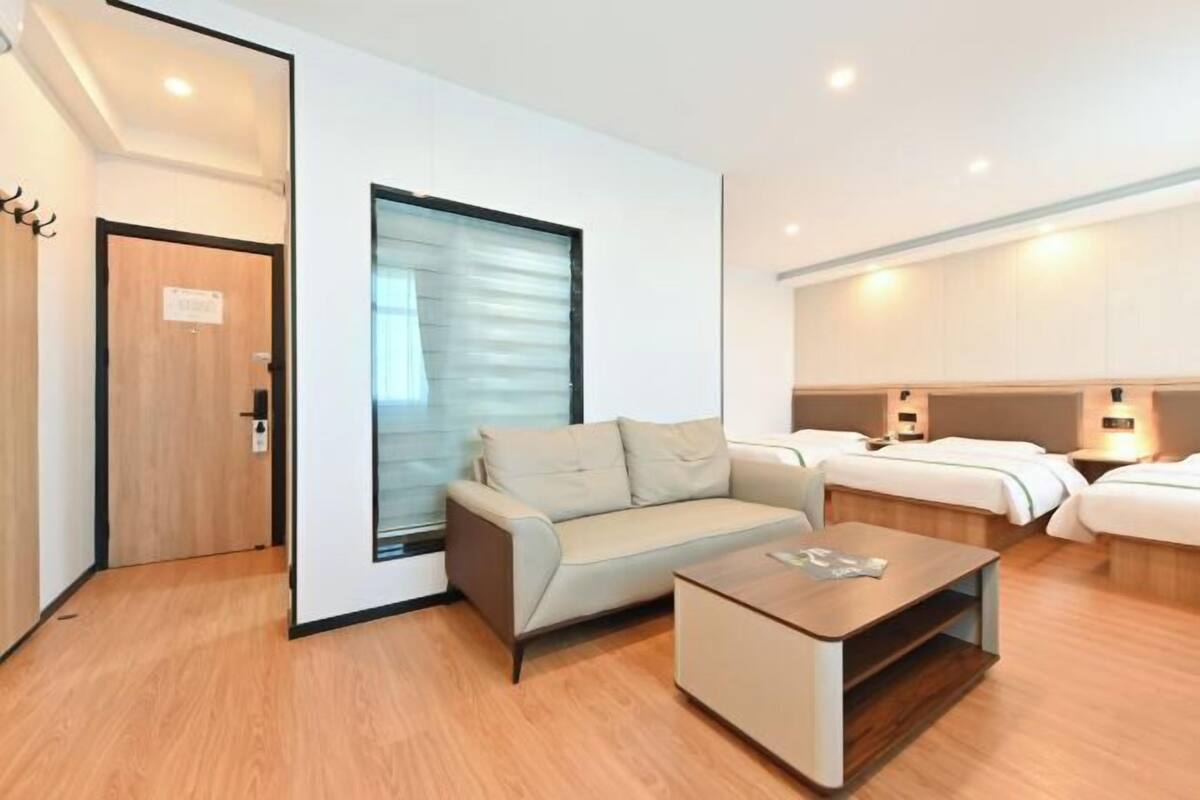 A modern hotel room with a sofa, a coffee table, and two beds.