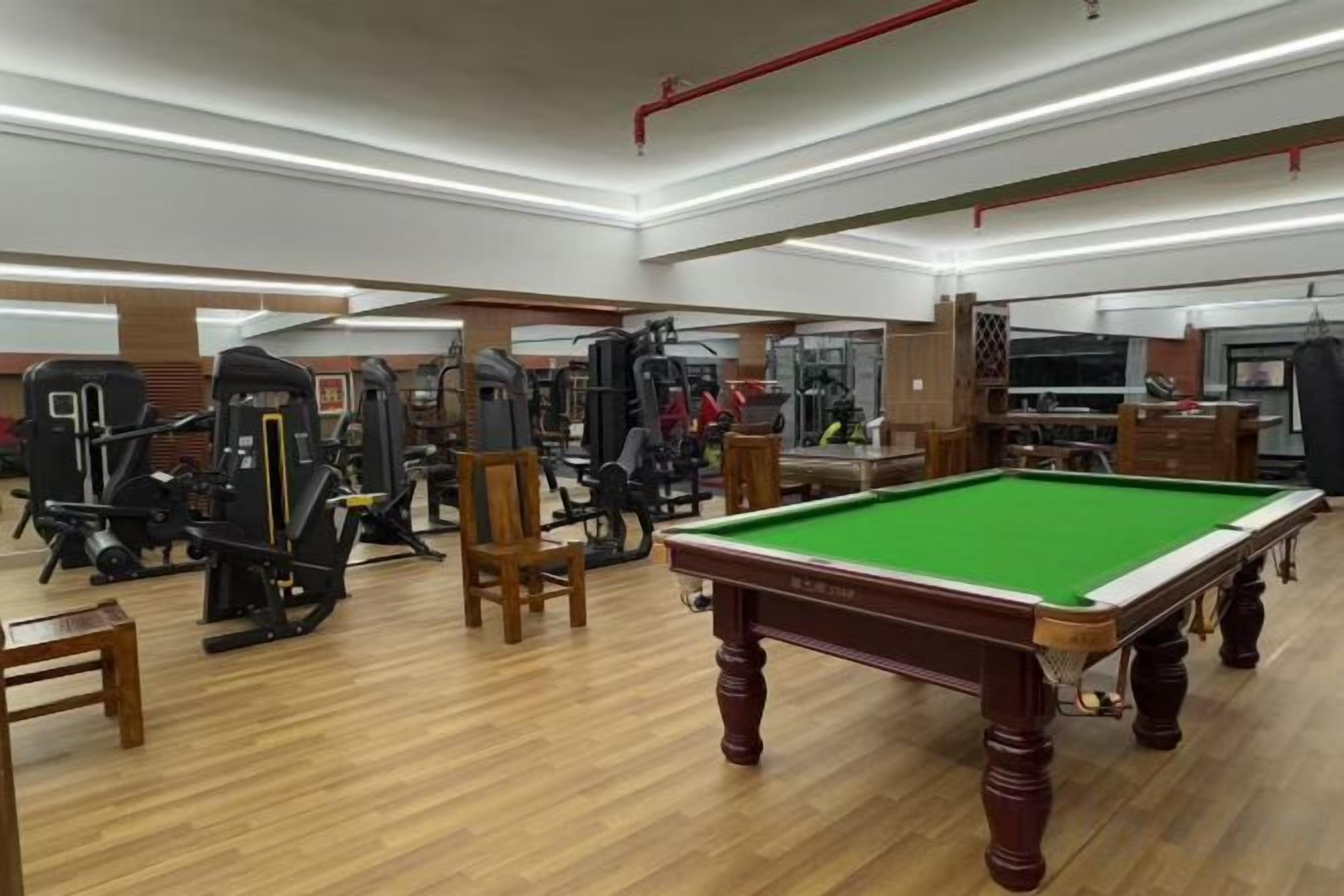 A gym with exercise equipment, a pool table, and a billiards table.