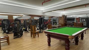 Une salle de sport équipée de matériel d’exercice, ainsi qu’une table de billard et une table de jeu de fléchettes.