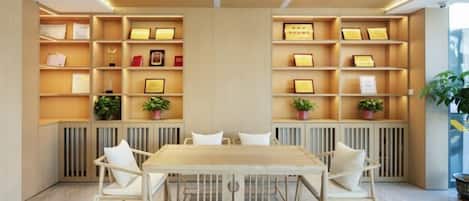A modern interior with a wooden table and chairs, shelves with framed certificates, and potted plants.