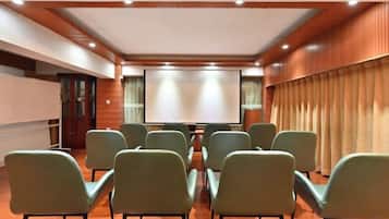 A conference room with a projector screen, rows of chairs, and a wooden ceiling.