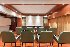 A conference room with a projector screen, rows of chairs, and a wooden ceiling.