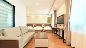 A modern hotel room with a sofa, a coffee table, a desk with a chair, a TV, and a bed. - GreenTree Inn (Fengtai Beijing Dongda Street) (Beijing)