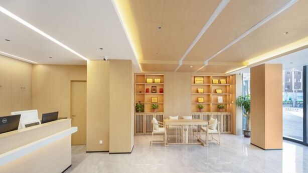 A modern reception area with a reception desk, seating area, and shelving with framed items. - GreenTree Inn (Fengtai Beijing Dongda Street) (Beijing)