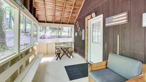 Eine Holzhütte mit Holzinnenausstattung, einer Bank, einem Tisch und Blick ins Freie.