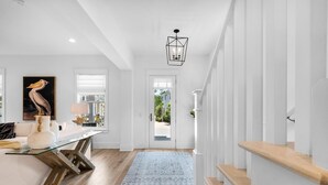 Een modern interieur met een glazen eettafel, witte muren en een trap.