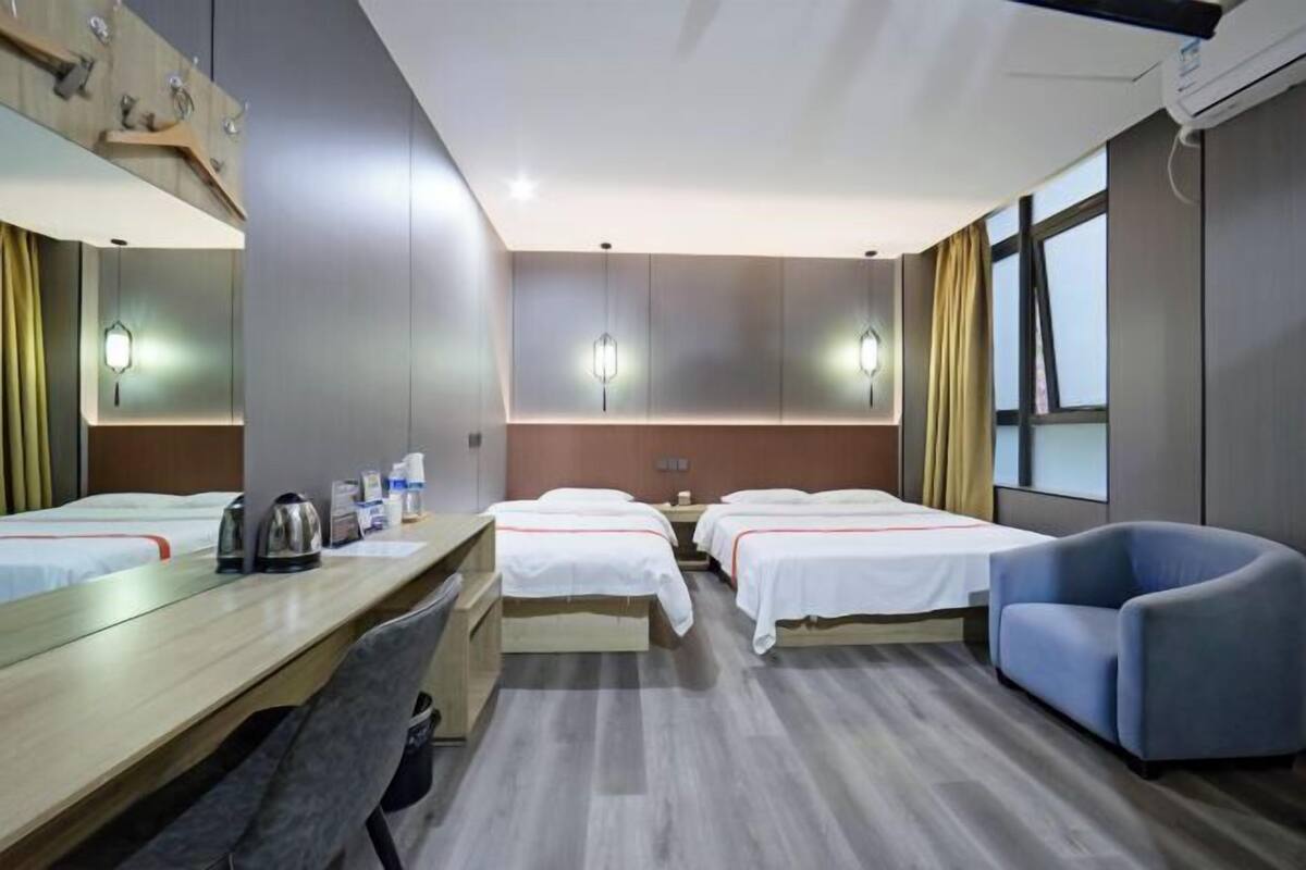 Une chambre d’hôtel avec deux lits, un bureau, une chaise, un miroir et une fenêtre.
