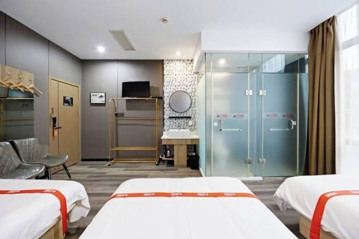 Une chambre d’hôtel avec deux lits, un bureau, une chaise, une télévision, un miroir et une armoire.